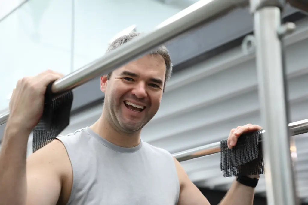 Smiling client holding the bar on a Pilates trapeze table